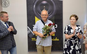 Dyrektor muzeum, Marek Chełminiak z kwiatami i burmistrz Solca Kujawskiego na tle plakatu wystawy.