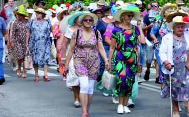 Idzie grupa seniorów w kolorowych kapeluszach