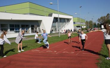 Uczniowie biegną na bieżni lekkoatletycznej - na mecie pomiar czasu.