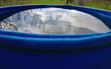 Fragment plastikowej beczki z deszczówką.