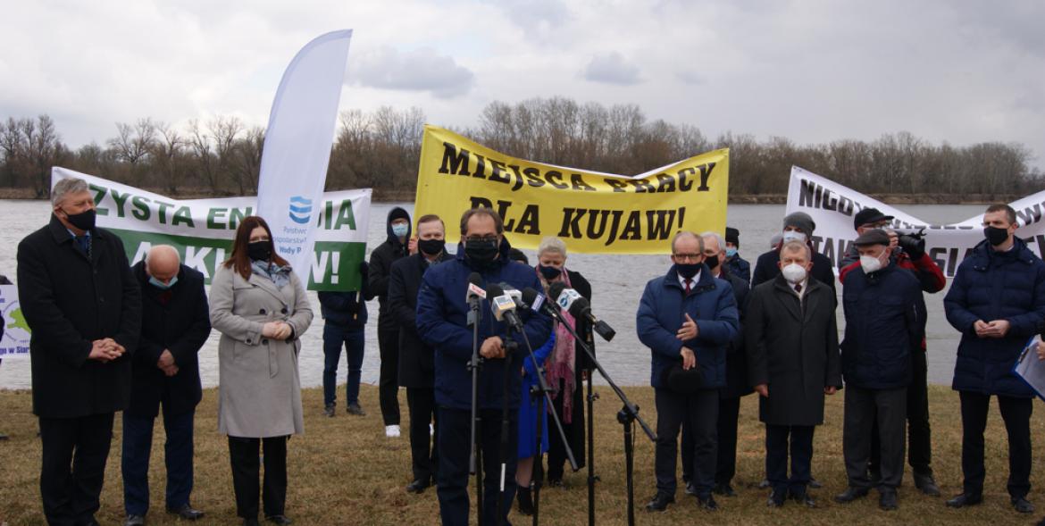 Uczestnicy spotkania na tle transparentów i Wisły.