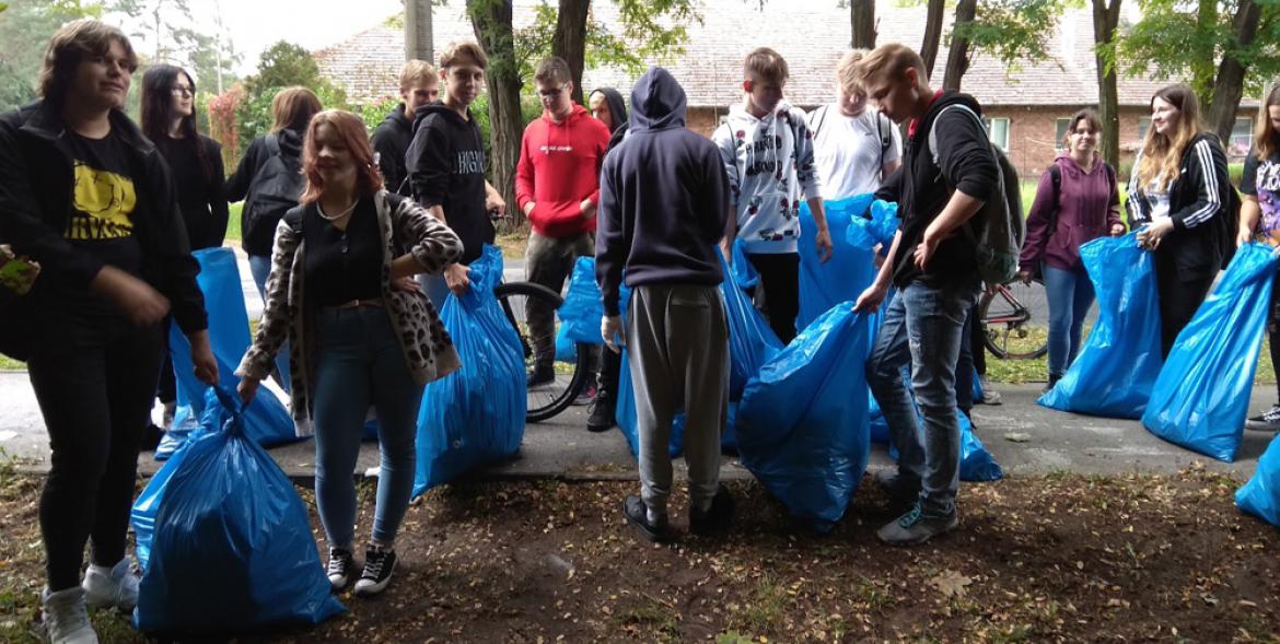 Uczniowie w czasie sprzątania z napełnionymi workami na śmieci.