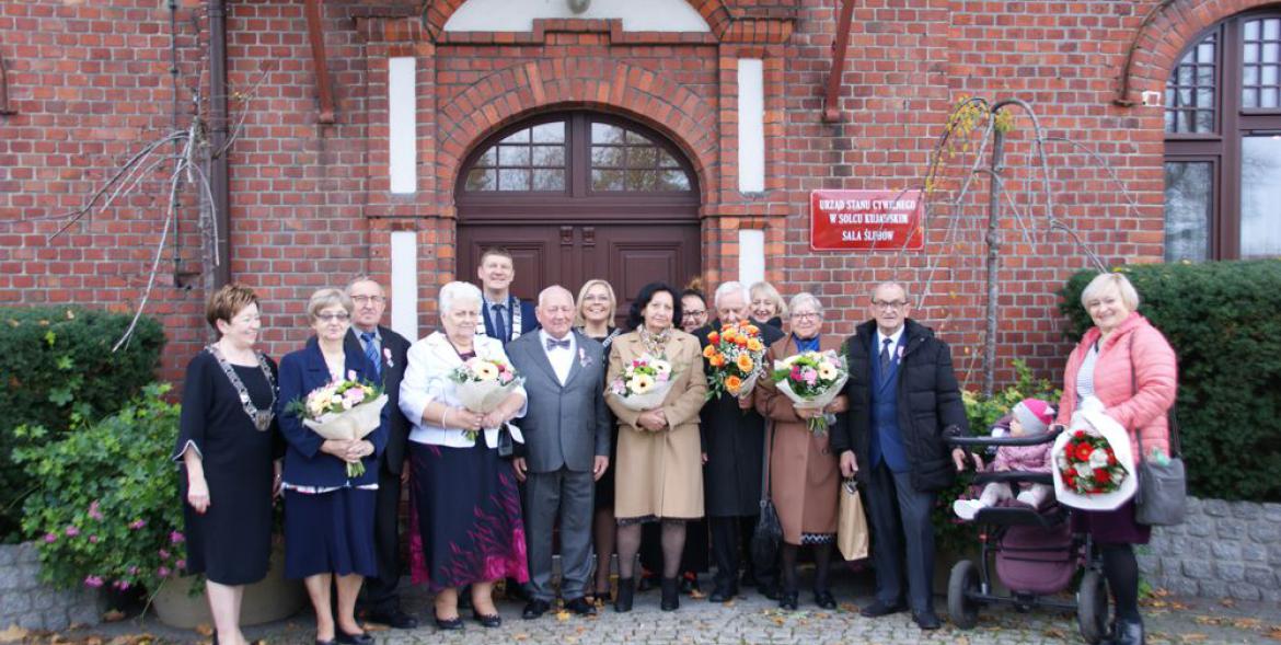 Uczestnicy uroczystości pozują do wspolnego zdjęcia przed urzędem.