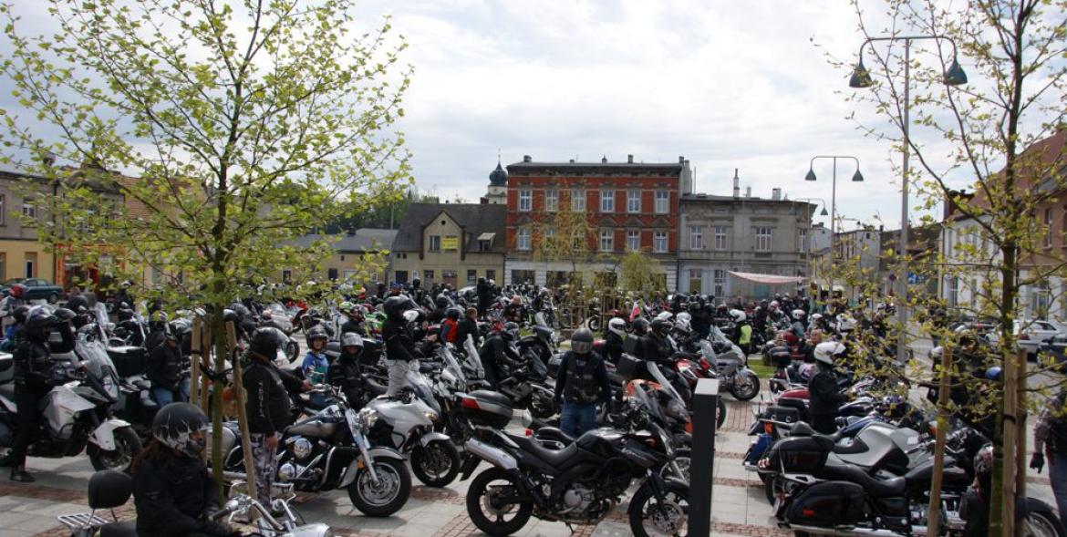 Motocykliści na motorach pozują na rynku do wspólnej fotografii.