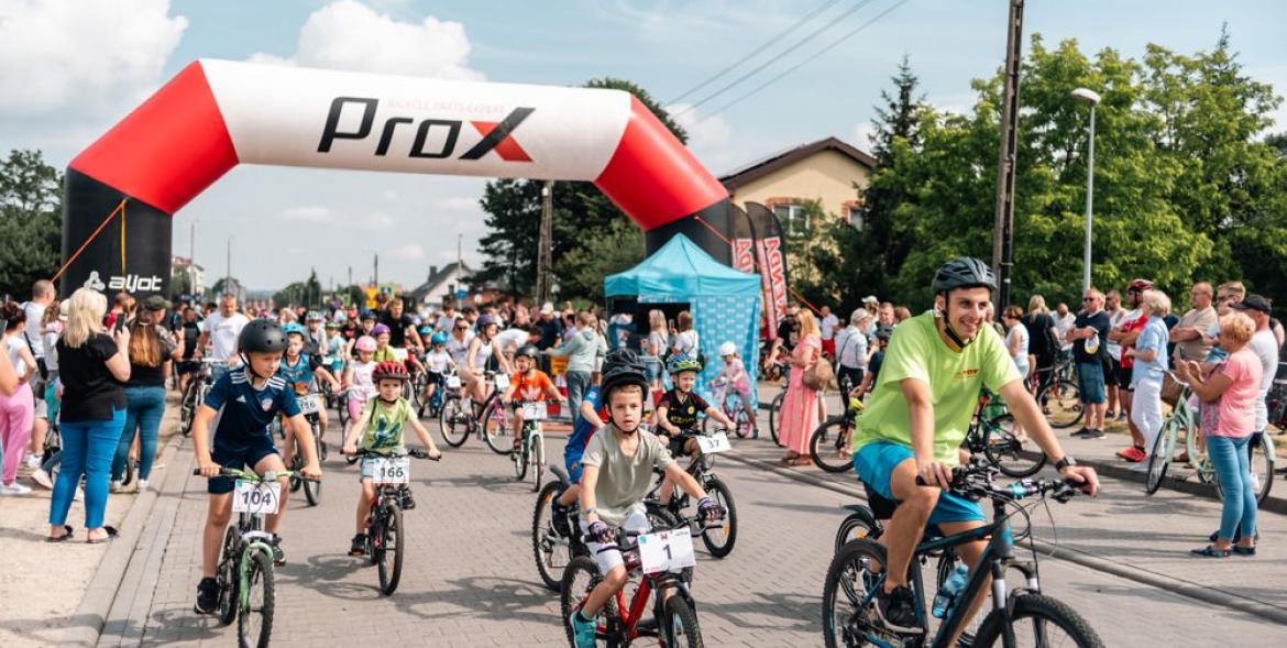 Uczestnicy wyścigu rowerowego ruszają z bramy startowej.