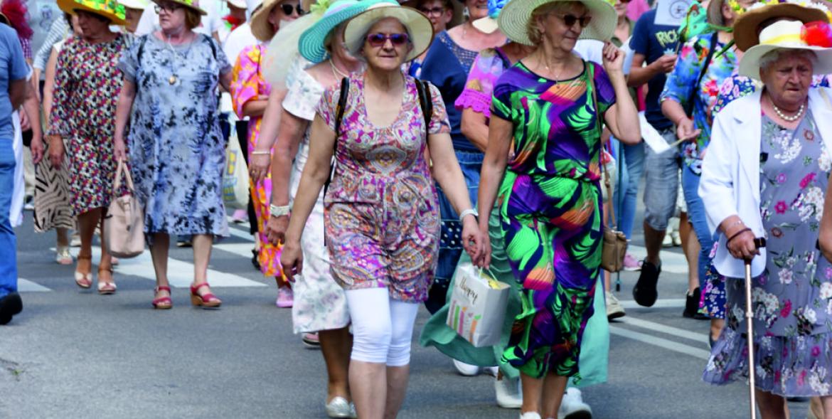 Idzie grupa seniorów w kolorowych kapeluszach