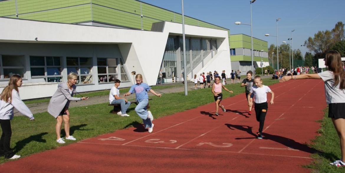 Uczniowie biegną na bieżni lekkoatletycznej - na mecie pomiar czasu.