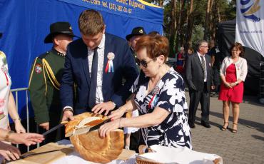 Burmistrz i przeowdniczący rady miejskiej kroją chleb.