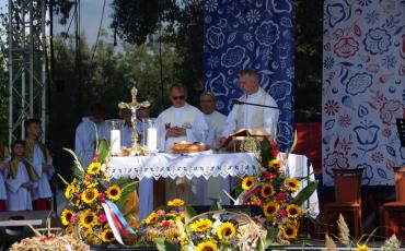 Msza. Ołtarz na scenie. Za ołtarzem obsługa liturgiczna - księża i ministranci