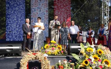 Przemaiw burmistrz. Obok starostowie dożynek, zastęca i przewodniczący rady.